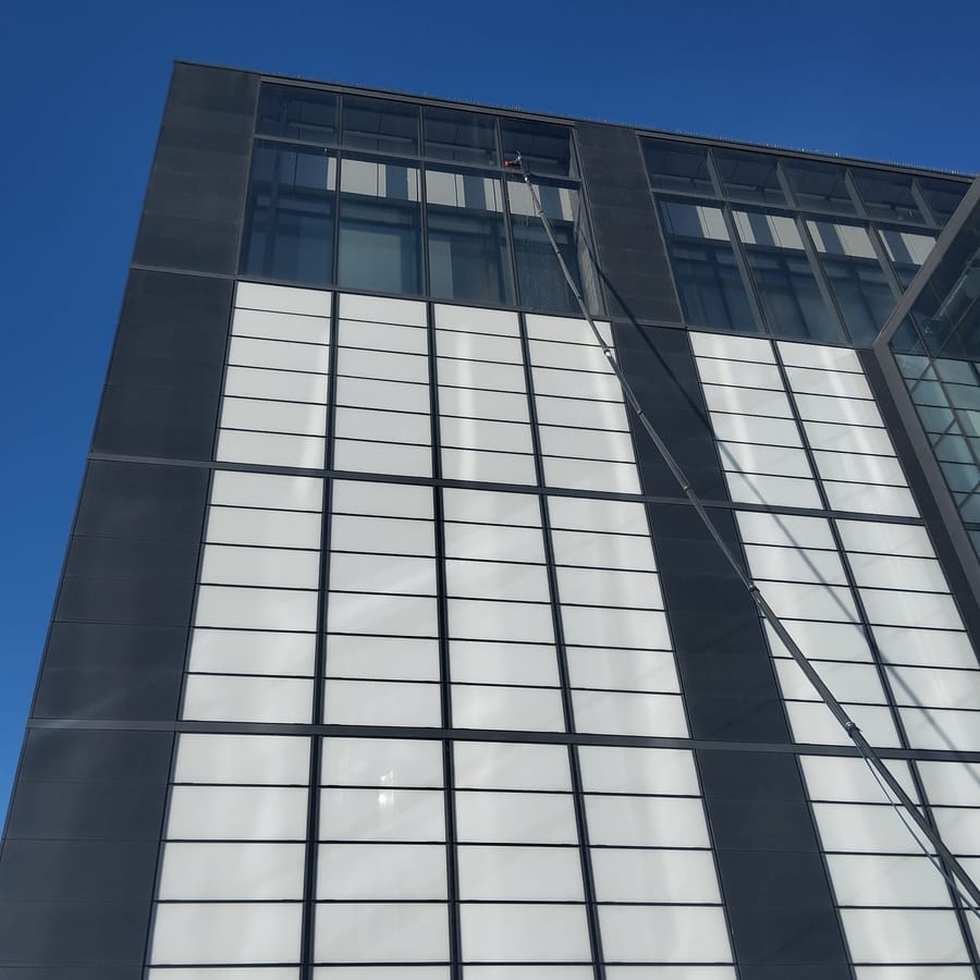 Mycie fasady nowoczesnego biurowca tyczką teleskopową